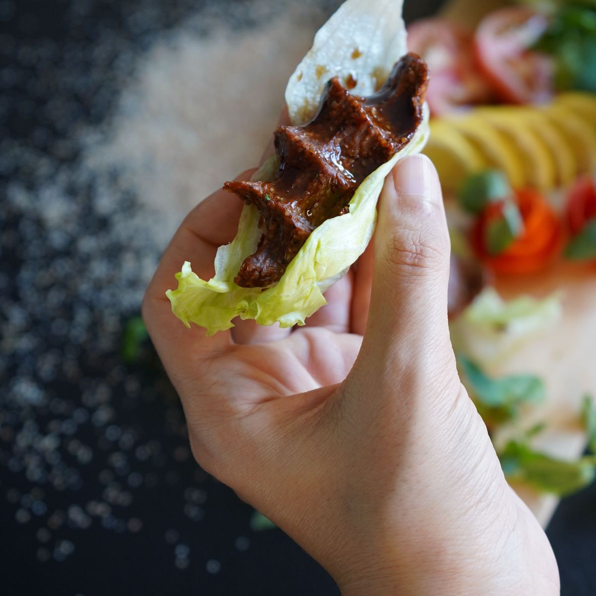 A çiğ köfte wrap held in one hand: spicy bulgur on lettuce inside thin lavash bread